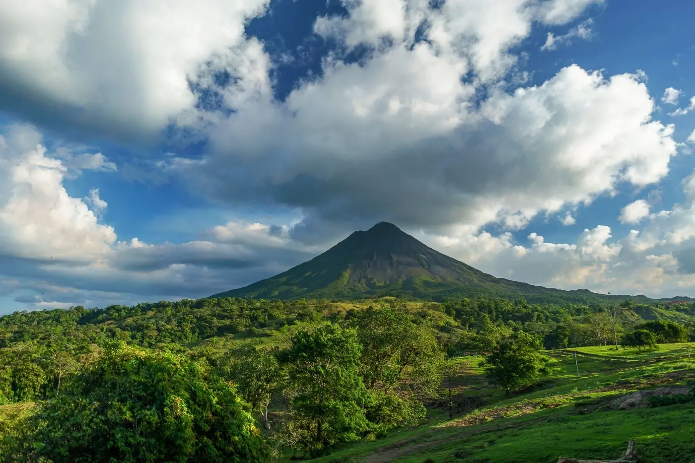 Arenal volcano rising above green farmland