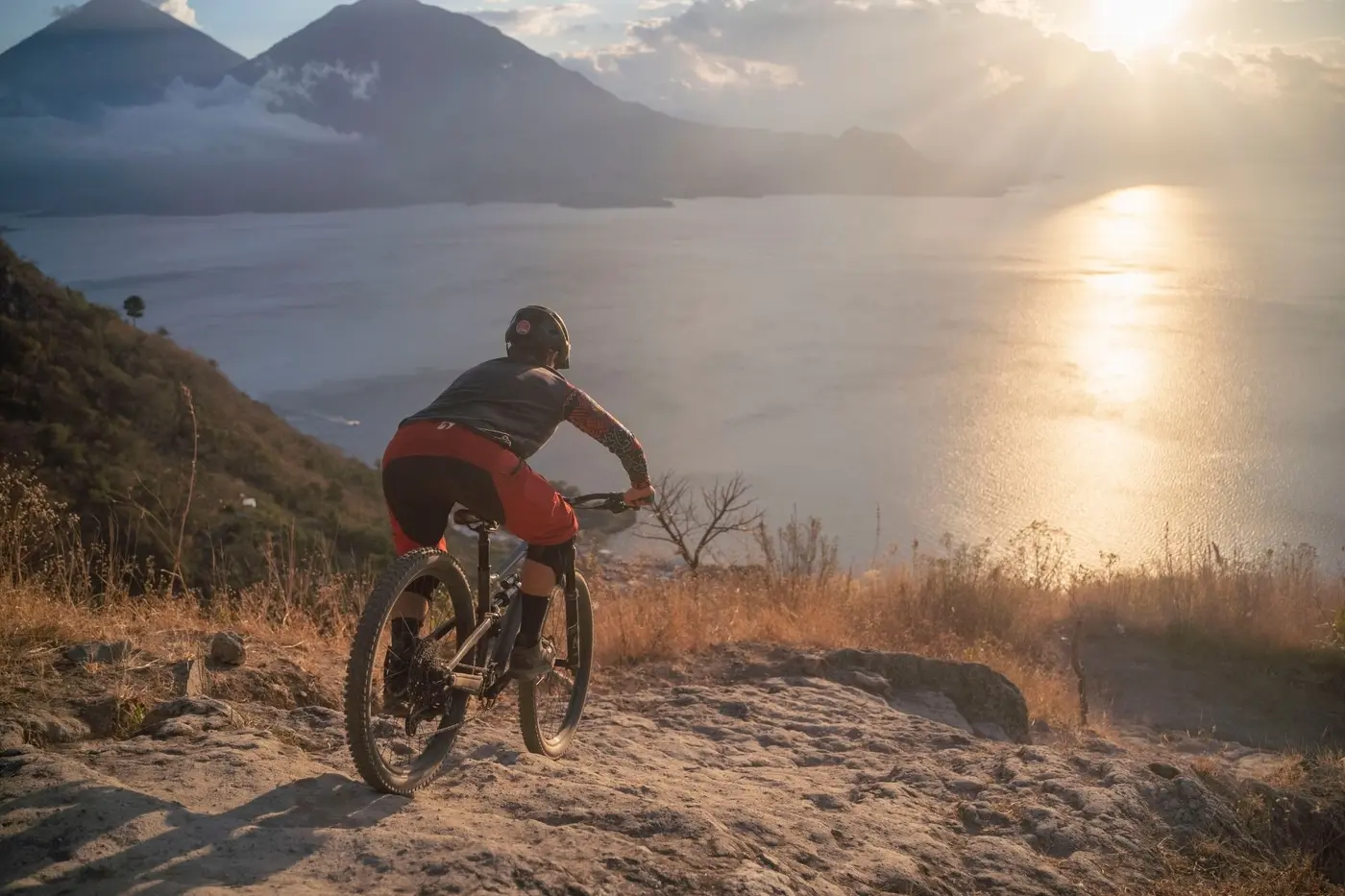 Rider carving a ridge trail at sunset above Lake Atitlán, Guatemala