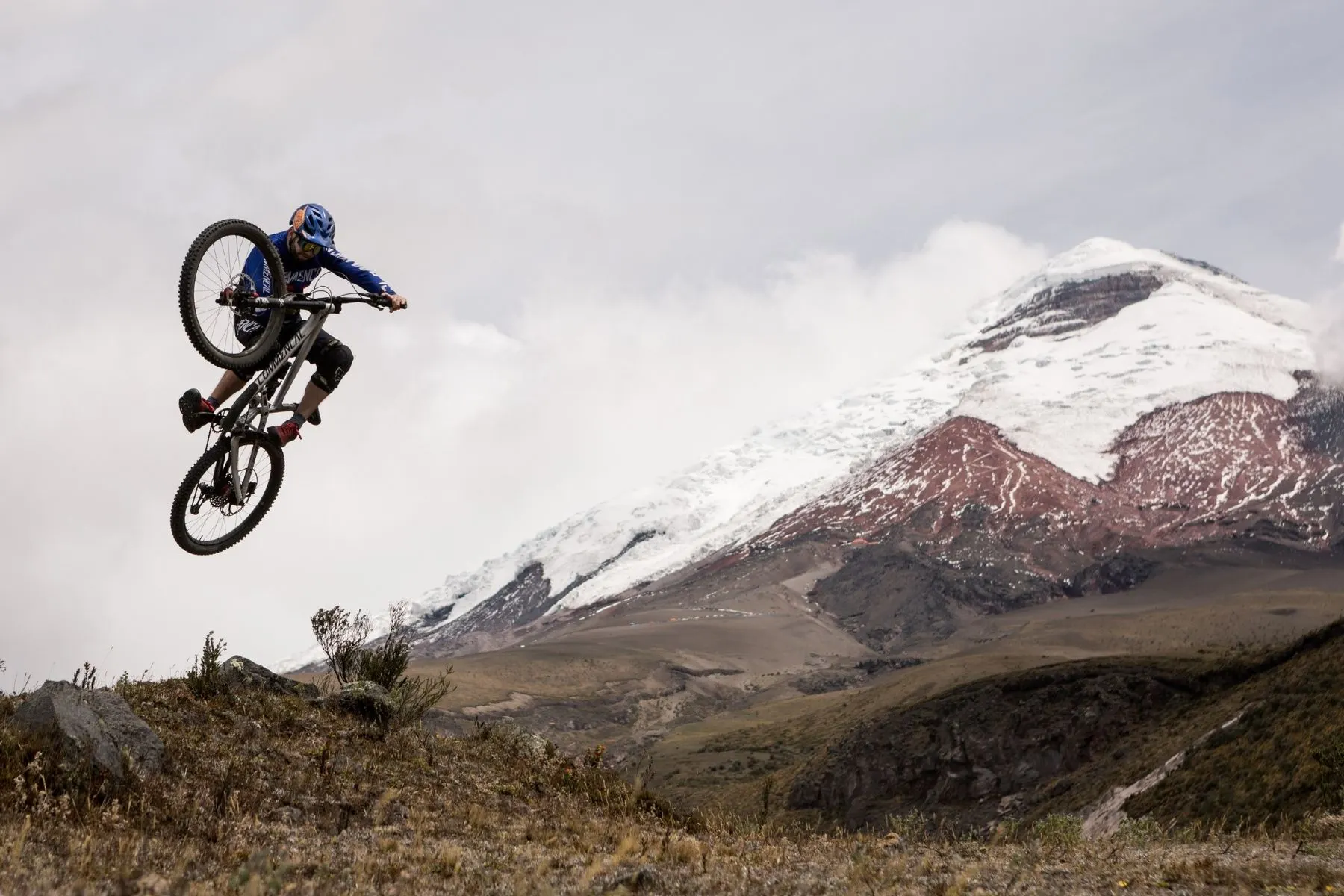 Rider airborne beside a snow-capped volcano